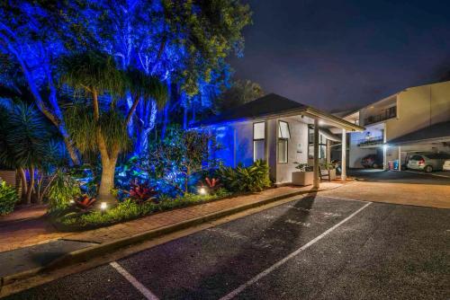 a house with blue lights on the side of it at The Oasis Apartments and Treetop Houses in Byron Bay