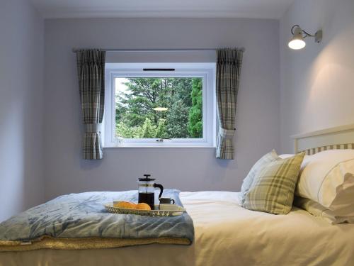 Una cama con ventana y una bandeja de fruta. en Woodland View en Whitewell