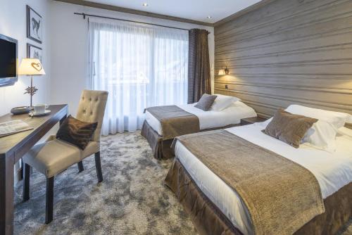 a hotel room with two beds and a desk at Hotel La Chaudanne in Méribel