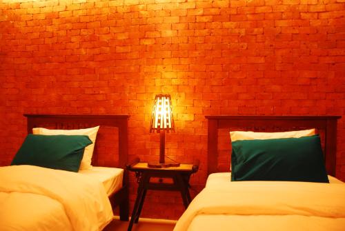 a bedroom with two beds and a brick wall at The White Elephant Home in Chiang Mai