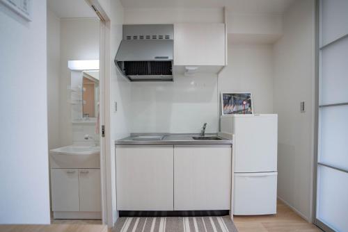 a white kitchen with a sink and a refrigerator at 震雲マンション105 in Osaka