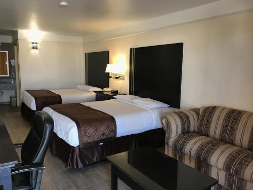 a hotel room with two beds and a couch at Texas Inn & Suites Pharr/San Juan in Pharr