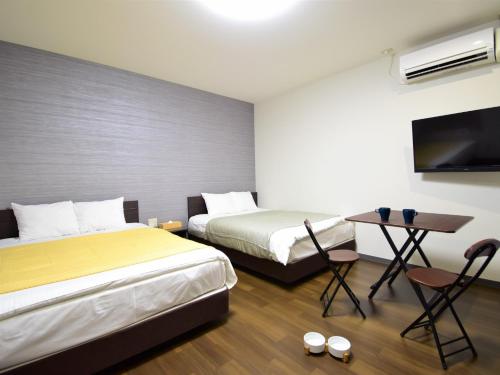 a room with two beds and a table and a tv at Regariain - Vacation STAY 85012 in Okayama