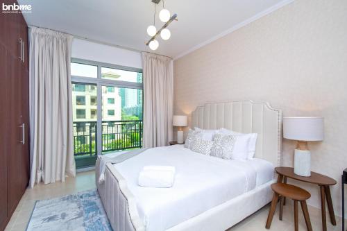 1 dormitorio con cama blanca y ventana grande en bnbmehomes - 2 BR Stunning Lake Views in Al Turia - 205 en Dubái