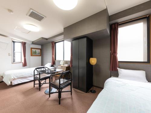 a hotel room with two beds and a table and chairs at Tabist My Room Tagajjo in Tagajo