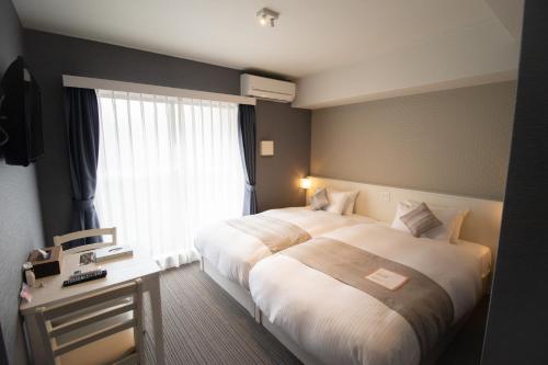 a hotel room with two beds and a window at Framboise KYOTO Hotel de charme in Kyoto