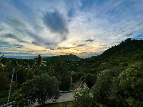 a view of a hill with trees and a cloudy sky at KohTao Studios Sunset in Koh Tao