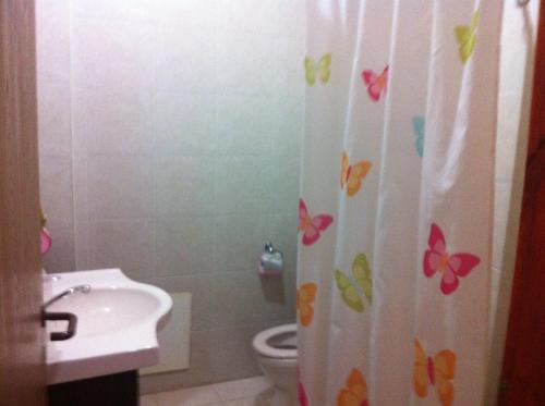 a bathroom with a toilet and a shower curtain with butterflies at Blueberry Rooms in Qasrîne