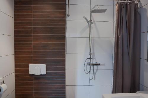 a shower in a bathroom with a tile wall at Mathurin Appartementen in Paramaribo