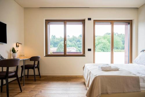 Bihotel في Comerzo: غرفة نوم بسرير ومكتب ونوافذ
