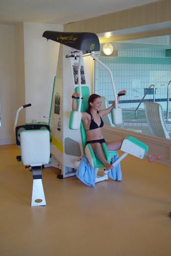 a woman is sitting on a gym machine at Hotel et Résidence Le Clos Cerdan in Mont-Louis