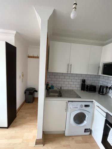 a white kitchen with a washing machine in it at Stylish & compact city center studio apartment in Norwich