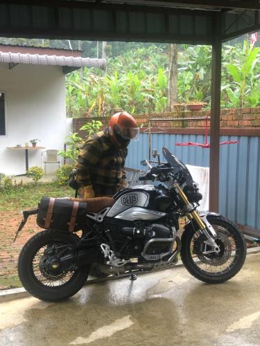 a man wearing a helmet sitting next to a motorcycle at MyDusun Chalet, Taiping, Perak, Malaysia in Taiping