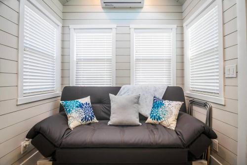 un divano in pelle in una camera con tre finestre di Delightful tiny home conveniently located a Apple Valley