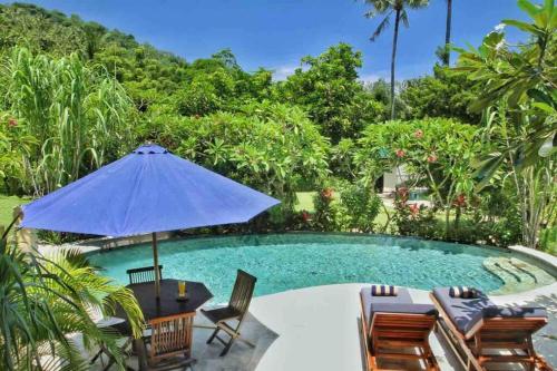 una piscina con sillas y sombrilla en Villa Serene & Spa Mangsit, en Mangsit