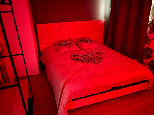 een rode slaapkamer met een rood bed met kussens bij L’Alsacienne room et spa in Lautenbach
