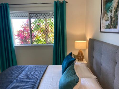 a bedroom with a bed with blue pillows and a window at Lakeside Central Apartment in Townsville
