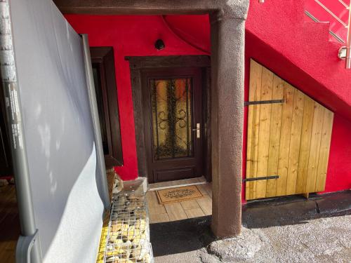 - un bâtiment rouge avec une porte marron et un escalier dans l'établissement L’Alsacienne room et spa, à Lautenbach