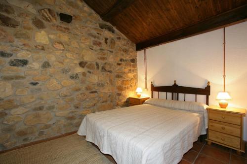 Casa Rural El Puente de Agues في Soto De Agues: غرفة نوم بسرير وجدار حجري
