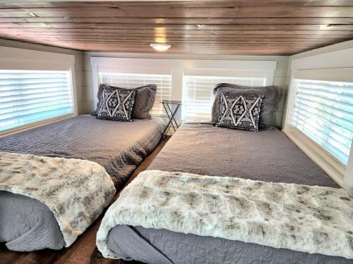 1 dormitorio con 2 camas y 2 ventanas en Peaceful Tiny Home with private deck-fire pit-bbq, en Apple Valley