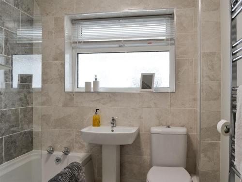 uma casa de banho com um lavatório, um WC e uma janela. em Brooklands em Talacre