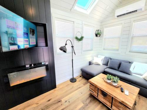 a living room with a couch and a table and a tv at NEW Nook Tiny Home with Deck Firepit Skylights in Apple Valley