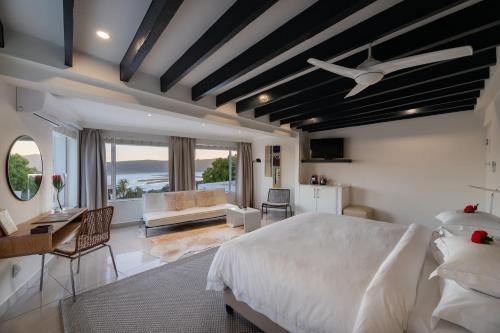 a bedroom with a large white bed and a desk at Villa Afrikana Guest Suites by Knysna Paradise Collection in Knysna