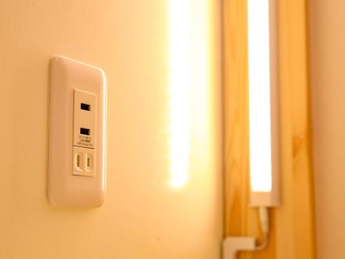 a white lightswitch on a wall next to a mirror at 14 Guesthouse Mt.Fuji in Fuji