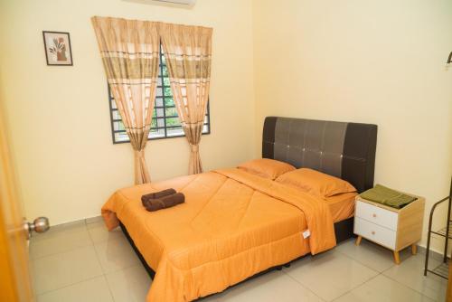 a bedroom with a bed with orange sheets and a window at Adorable 3-bedroom home with Wi-Fi, Netflix and BBQ grill in Rembau