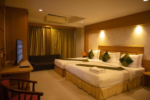 a hotel room with a large bed and a television at The ESSE Hotel Pattaya in Pattaya South