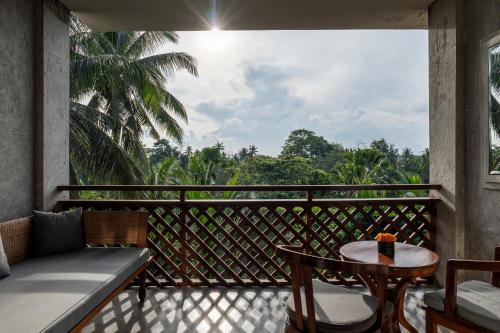 a balcony with a table and a view of the forest at Adiwana Bisma in Ubud
