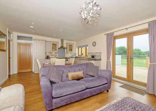 a living room with a purple couch and a kitchen at Larkshayes Cottages in Hawley Bottom