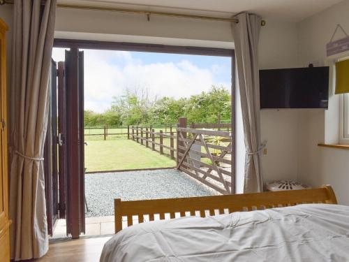 a bedroom with a sliding glass door with a view of a gate at The Willows in Hambleton