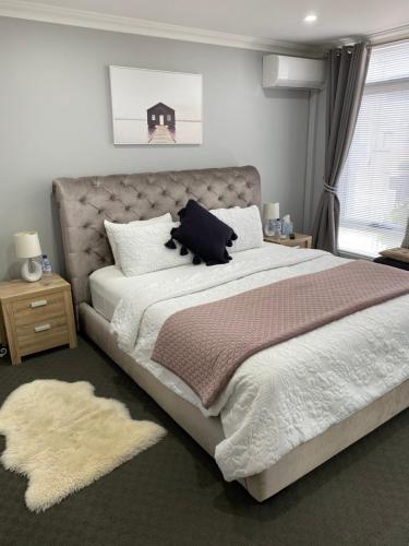 a bedroom with a large bed with a blanket and pillows at The Hutt on Mandurah Marina in Mandurah