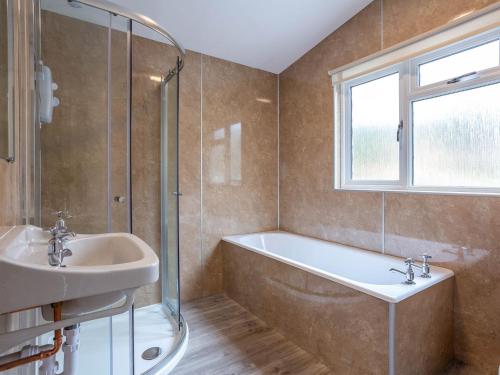 a bathroom with a tub and a sink and a window at Kilninver - Uk31537 in Kirkhill