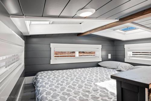 Under The Sea Tiny Home في Apple Valley: غرفة نوم صغيرة بها سرير ونوافذ