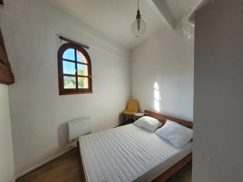 ein weißes Schlafzimmer mit einem Bett und einem Fenster in der Unterkunft Cadre exceptionnel niché sous les toits dans le quartier historique in Albi