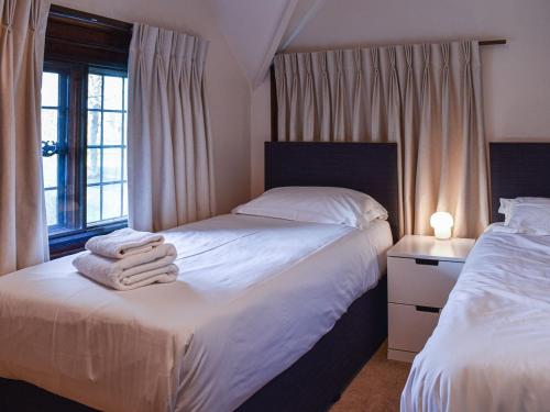 a bedroom with two beds with white sheets and a window at The Lodge in Coton