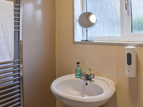 a bathroom with a sink and a mirror and a window at The Lodge in Coton
