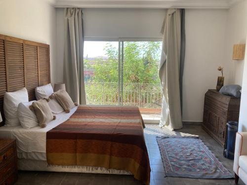 een slaapkamer met een bed en een groot raam bij Le Patio Du Lac in Lalla Takerkoust