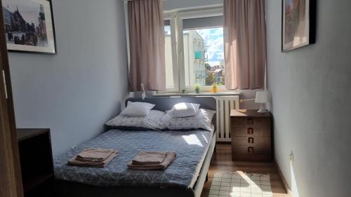 niewielka sypialnia z łóżkiem i oknem w obiekcie Apartament Okno na Zamek w mieście Malbork