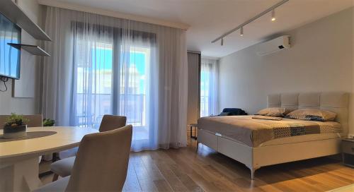 a bedroom with a bed and a table and a dining room at Green Apartments Podgorica With Garage in Podgorica