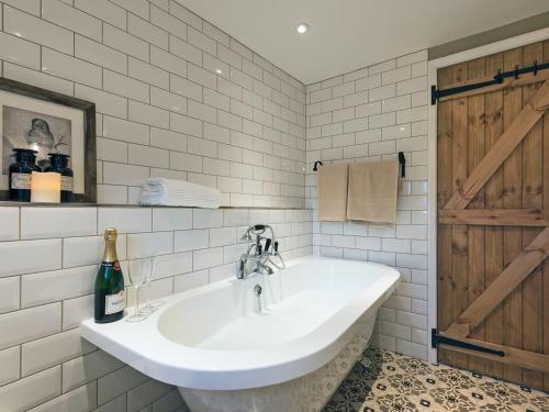 a white bathroom with a sink and a bottle of wine at Crescent Cottage in Askham