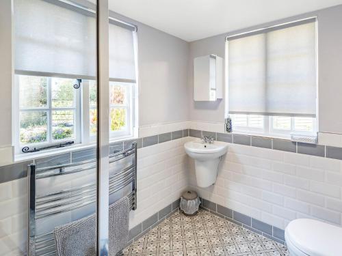 a bathroom with a toilet and a sink and two windows at Lion Gate Lodge in Horncastle