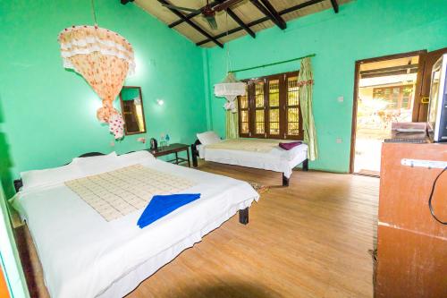 1 Schlafzimmer mit 2 Betten in einem Zimmer mit grünen Wänden in der Unterkunft Chitwan Gaida Lodge Pvt. Ltd. in Sauraha