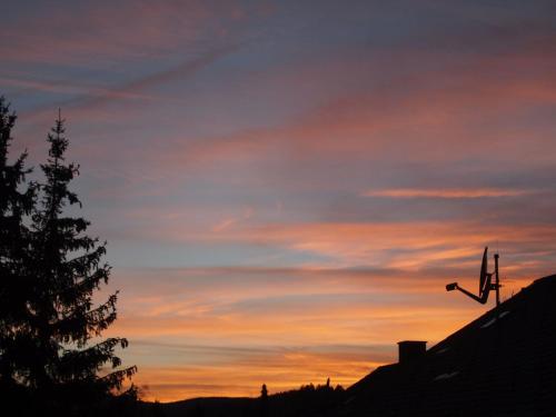un coucher de soleil avec une croix sur le toit d'une maison dans l'établissement FeWo Cheny in Titisee, à Titisee-Neustadt