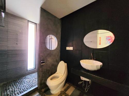 a black bathroom with a toilet and a sink at Surintra Boutique Resort in Surin Beach