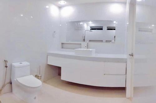 a white bathroom with a toilet and a sink at ABIZA Homestay in Pañge