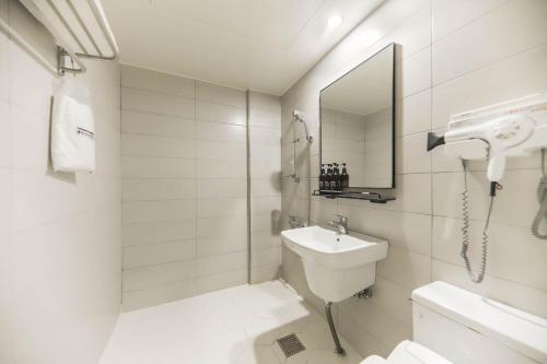 a white bathroom with a sink and a mirror at Hotel Yeosu Yam Hakdong in Yeosu