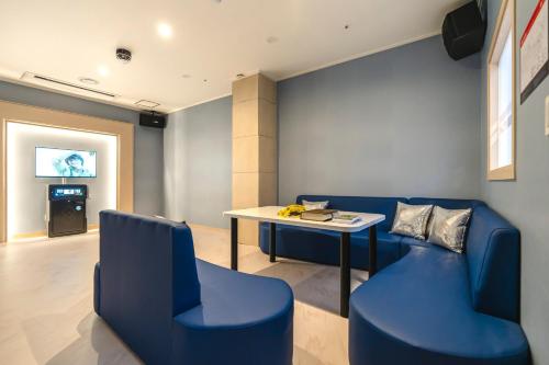 a room with blue chairs and a table and a television at Hallim Resort in Jeju